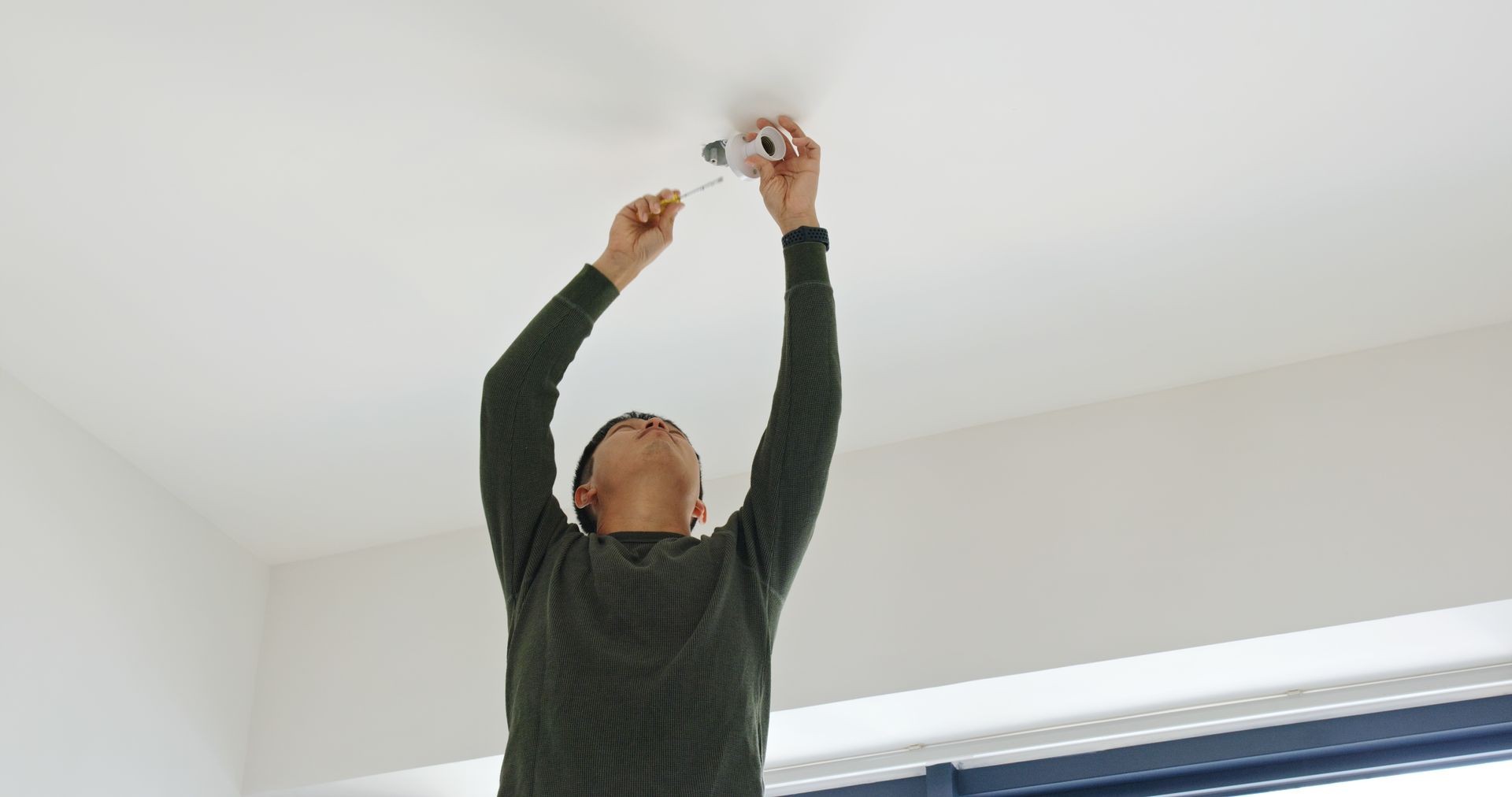 Man install lamp onto the ceiling at home